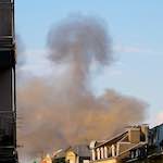 image: smoke rises across the rooftops